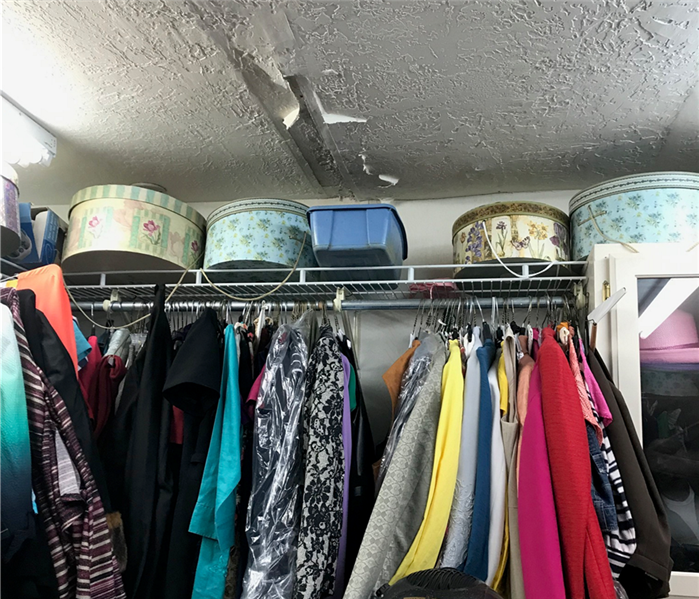 closet with clothes ceiling damage