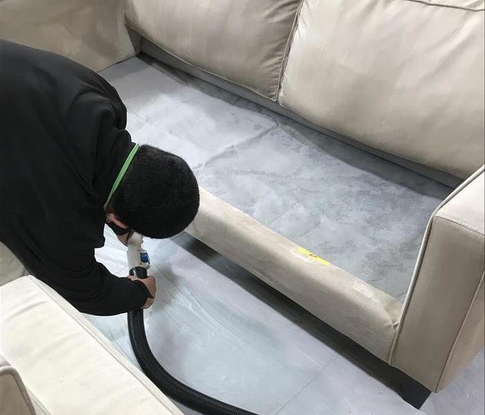 man in black cleaning couch